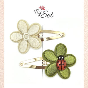 crème en zwarte bloem op haarspeldje met een lieveheersbeestje